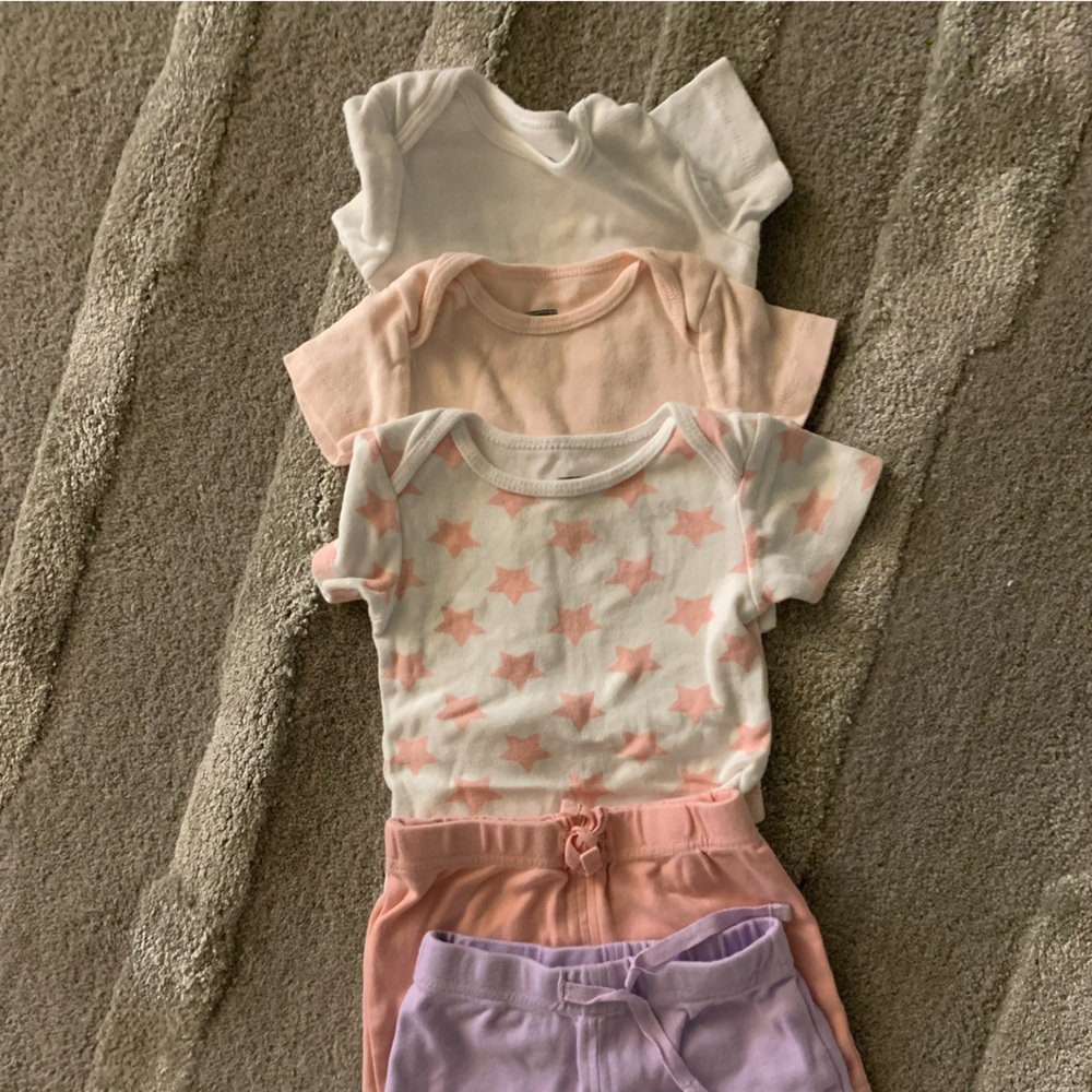 Three baby girl onesies and two pairs of shorts